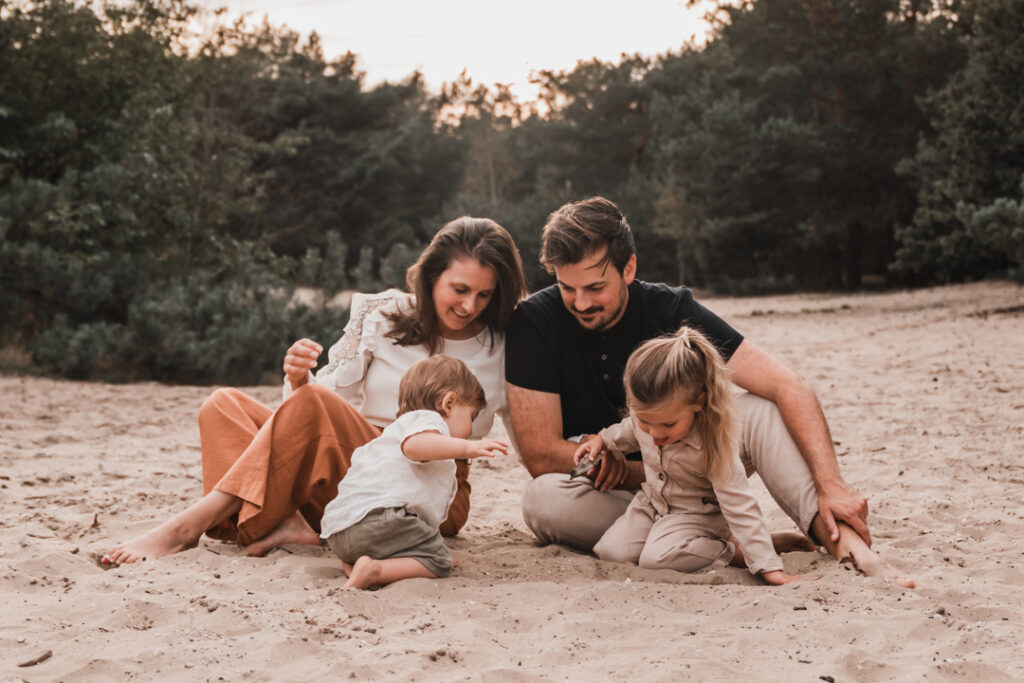 Foto van een gezin zittend in het zand tijdens gezinsfotoshoot door fotograaf Sabrina Wennekes Nijmegen